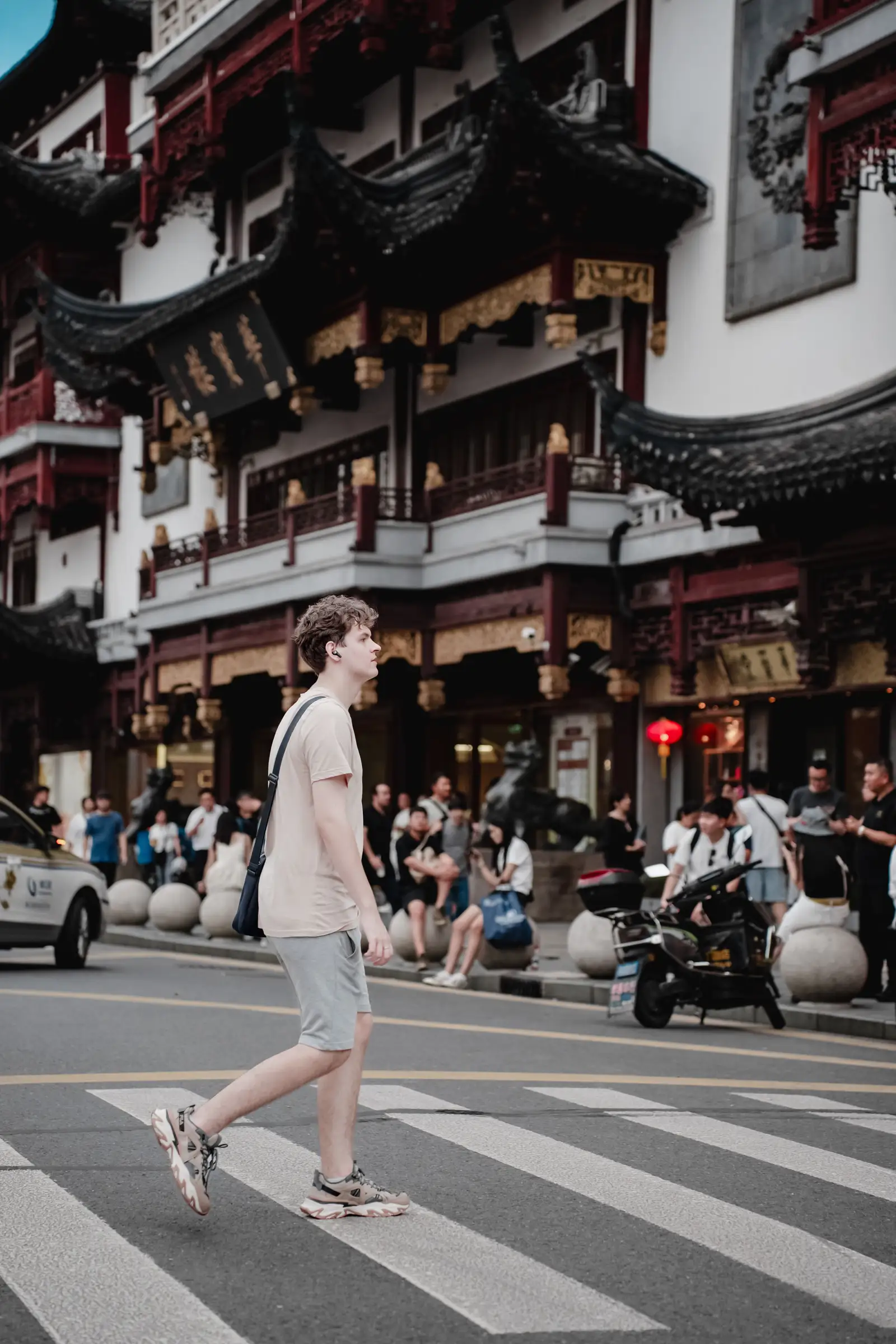 A traveller crossing the street in front of the carved facades of Yu Garden bazaar